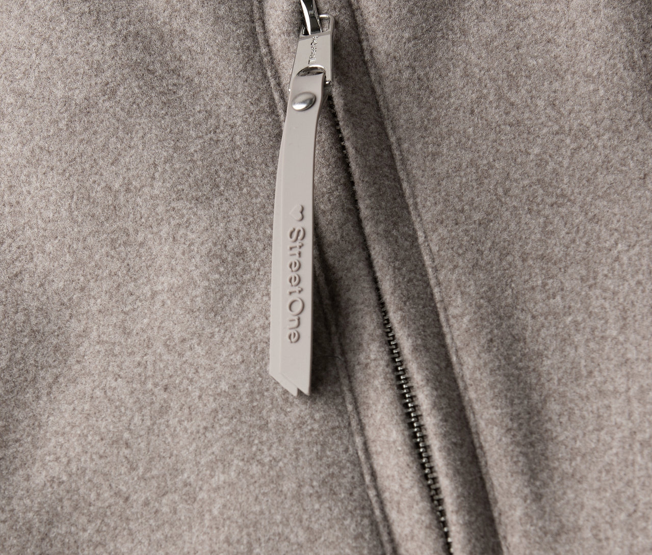 Detailansicht eines Street One Kurzmantels mit Reißverschluss und Anhänger.