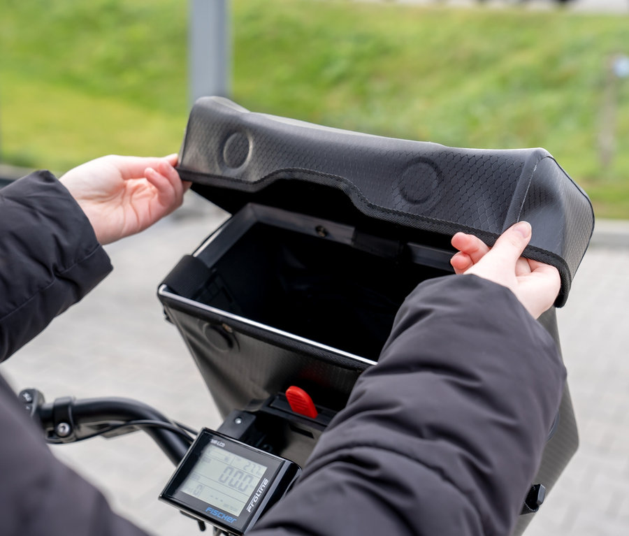 Person öffnet FISCHER Lenkertasche PLUS+ Terra auf einem Fahrradlenker.