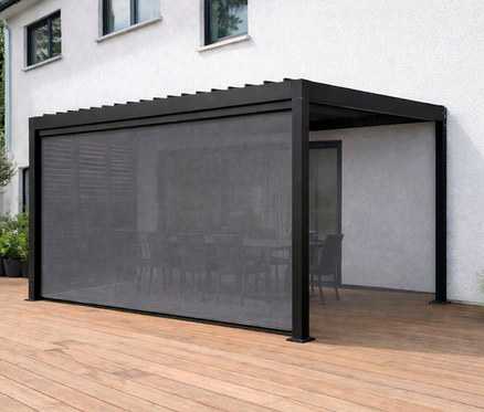 Leco Lamellenpergola 360 x 300 cm steht auf einer Holzterrasse vor einem weißen Haus. Ein Rollo ist heruntergelassen.
