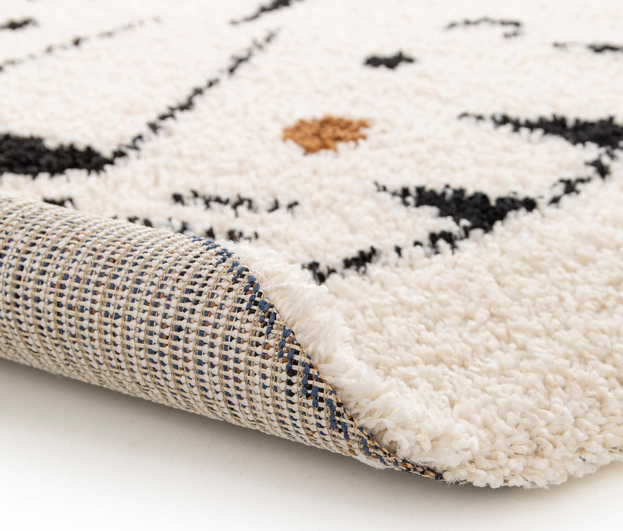 Detailansicht eines Kinderteppichs NOMAD Tiger, Ø ca. 135 cm, der an der Kante aufgerollt ist.