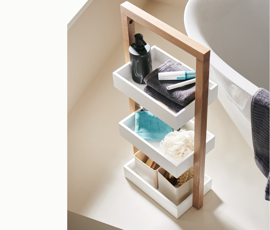 Ein vierstöckiges Standregal mit einem elektrischen Augenbrauenstyler, einem elektrischen Trimmer, einem marmorierten Seifenspender, Jacquard-Gästehandtüchern, zwei Organizer und Waschlappen.