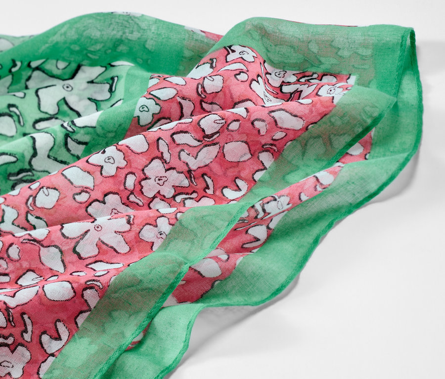 Detailansicht eines bedruckten Loop-Schals mit Blumenmuster in Grün und Rosa.