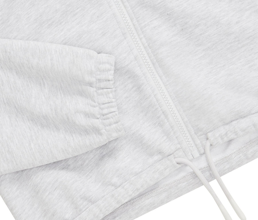 Detailansicht einer grauen Trainingsjacke mit Reißverschluss und Kordelzug.