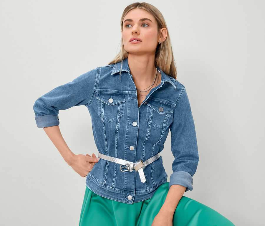 Blonde Frau posiert in Jeansjacke und Satinrock.