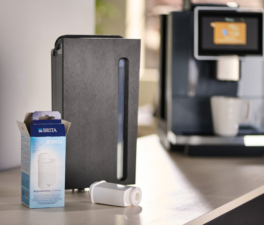 Eine Packung Brita AquaAroma Crema Filter neben einem Filter und einer Kaffeemaschine.