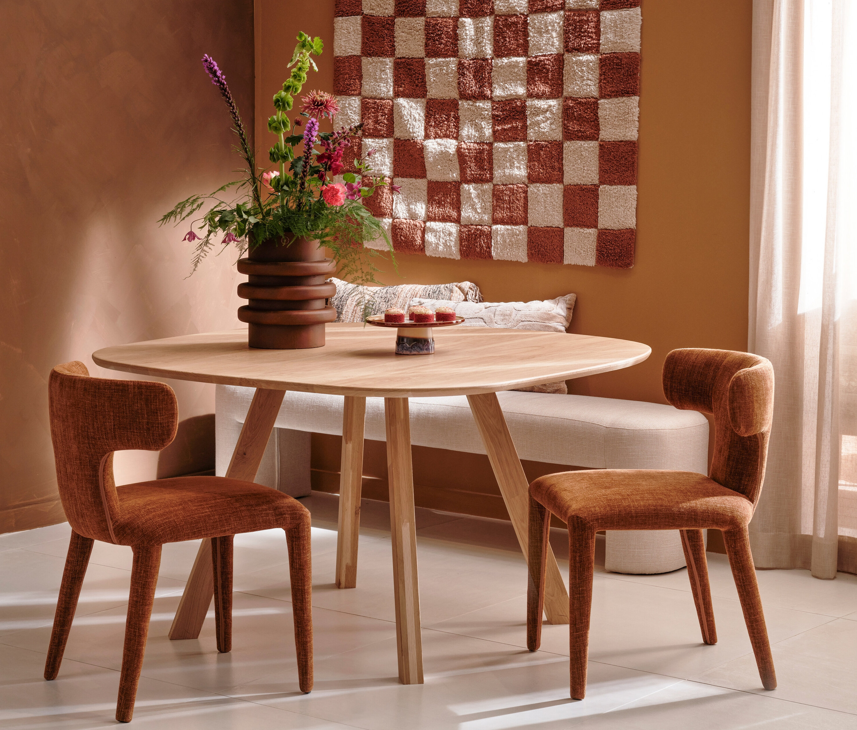 Zwei zimtfarbene BePureHome »Permit« Stühle stehen an einem runden Tisch. Auf dem Tisch steht eine Vase mit Blumen.