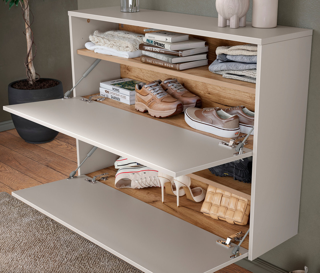 Zwei offene Schuhschrankfächer mit Schuhen, Büchern und Pullovern.