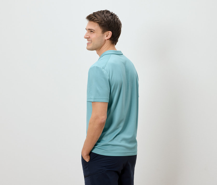 Mann von der Seite in hellblauem Poloshirt und dunkler Hose.