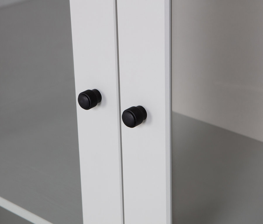 Nahaufnahme von zwei schwarzen Knöpfen an weißen Schranktüren.