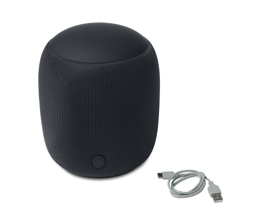 Ein anthrazitfarbener Design-Bluetooth®-Lautsprecher L und ein graues Ladekabel liegen auf einem weißen Hintergrund.