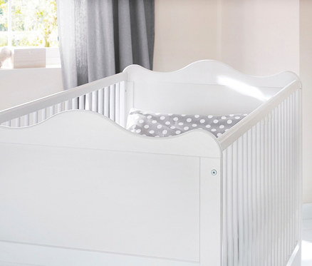 Nahaufnahme eines weißen Kinderbetts mit einem grauen Kissen mit Tupfen. Zu sehen ist das 3-teilige Pinolino Set »Florentina« breit.