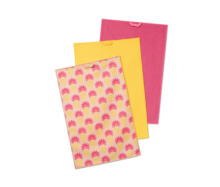 Drei Geschirrtücher: Eines mit Blumenmuster, eines gelb und eines pink.