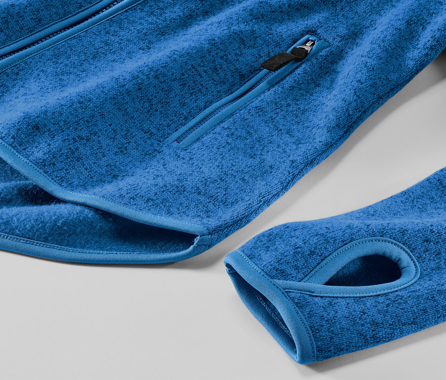 Detailansicht einer blauen Strickfleece-Jacke mit Reißverschlusstasche und Daumenloch.