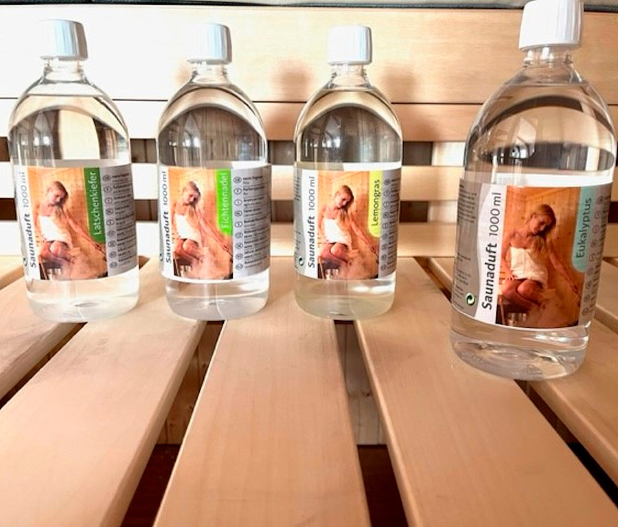 Vier Flaschen Karibu Sauna-Aufgusskonzentrat, 4x 1.000 ml, auf einer Holzfläche. Sie sind horizontal aufgereiht.