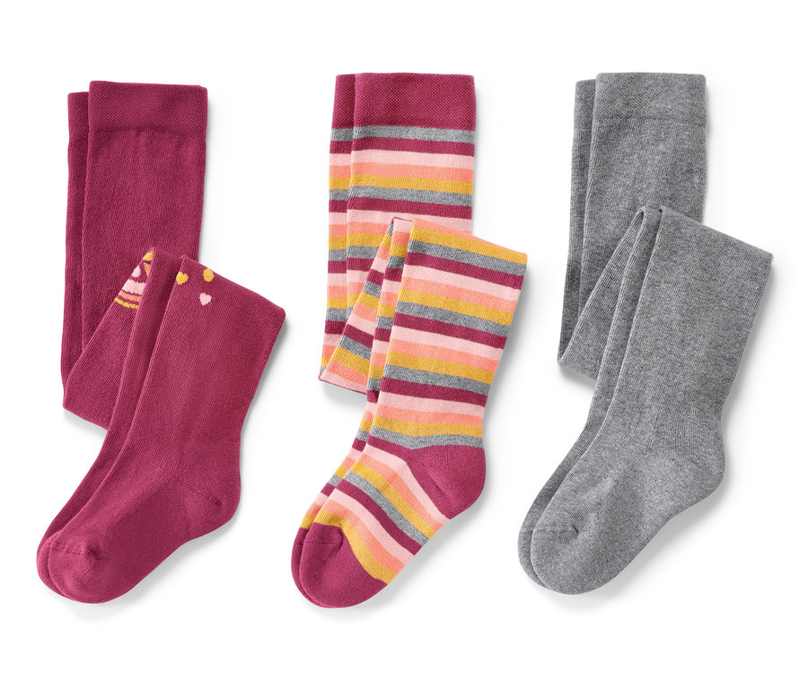 Drei Paar Kinder-Strumpfhosen, rosa, liegen auf einem weißen Hintergrund.