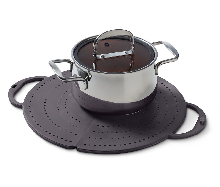 Ein Edelstahltopf mit Deckel steht auf einer lila Silikonunterlage mit Löchern.