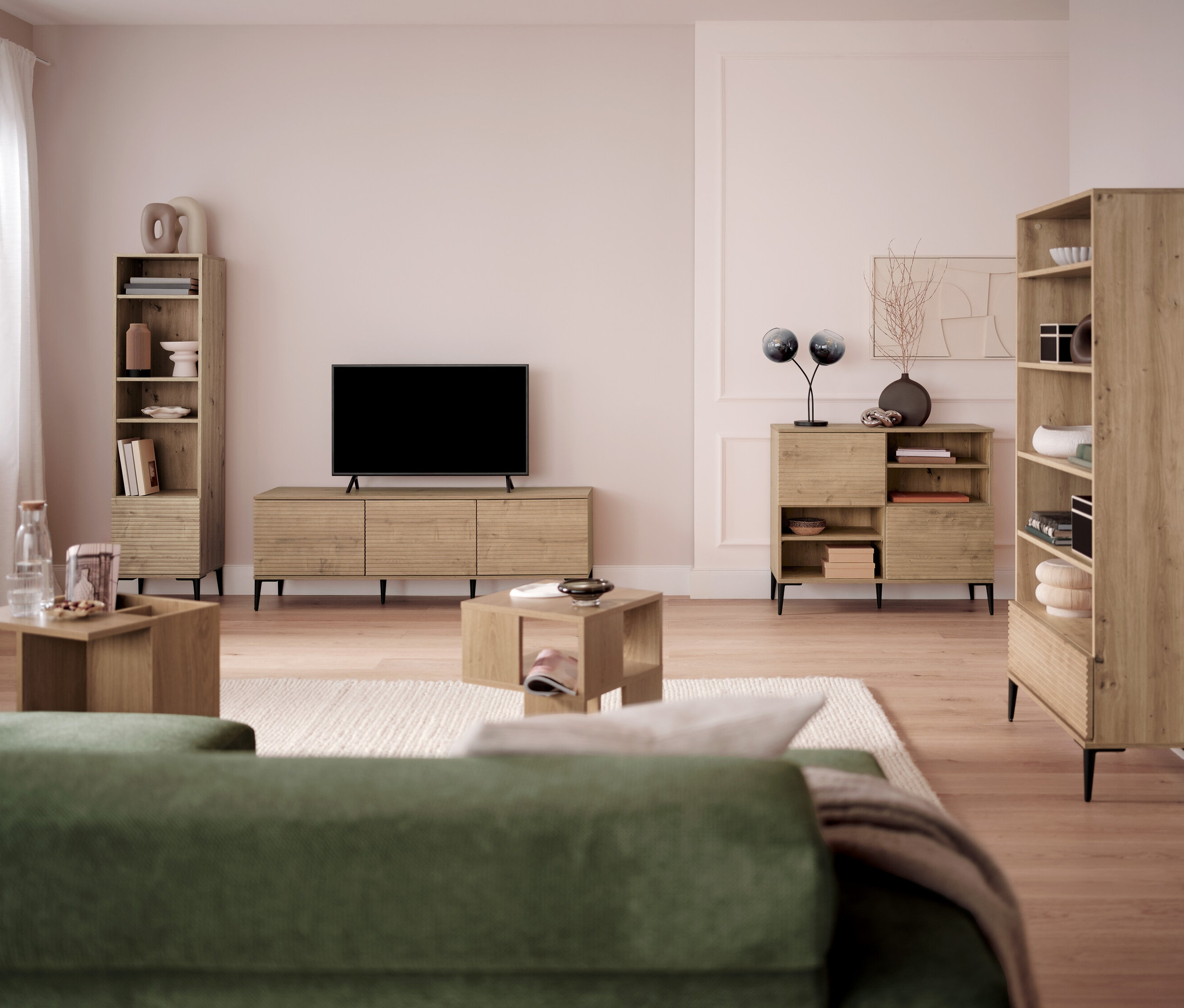 Wohnzimmer mit Fernseher, Bücherregalen und Couchtischen.