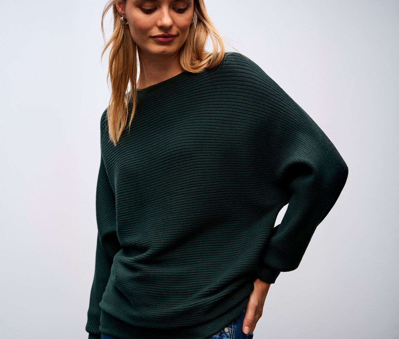 Frau trägt einen grünen Street One Strukturpullover und blaue Jeans.