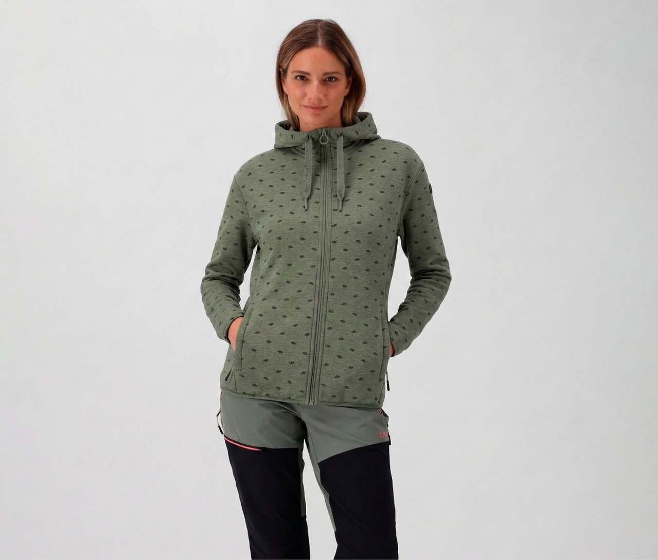 Frau mit Kapuze trägt eine avocado CMP Damen-Fleece-Jacke mit Kapuze und hat die Hände in den Taschen.