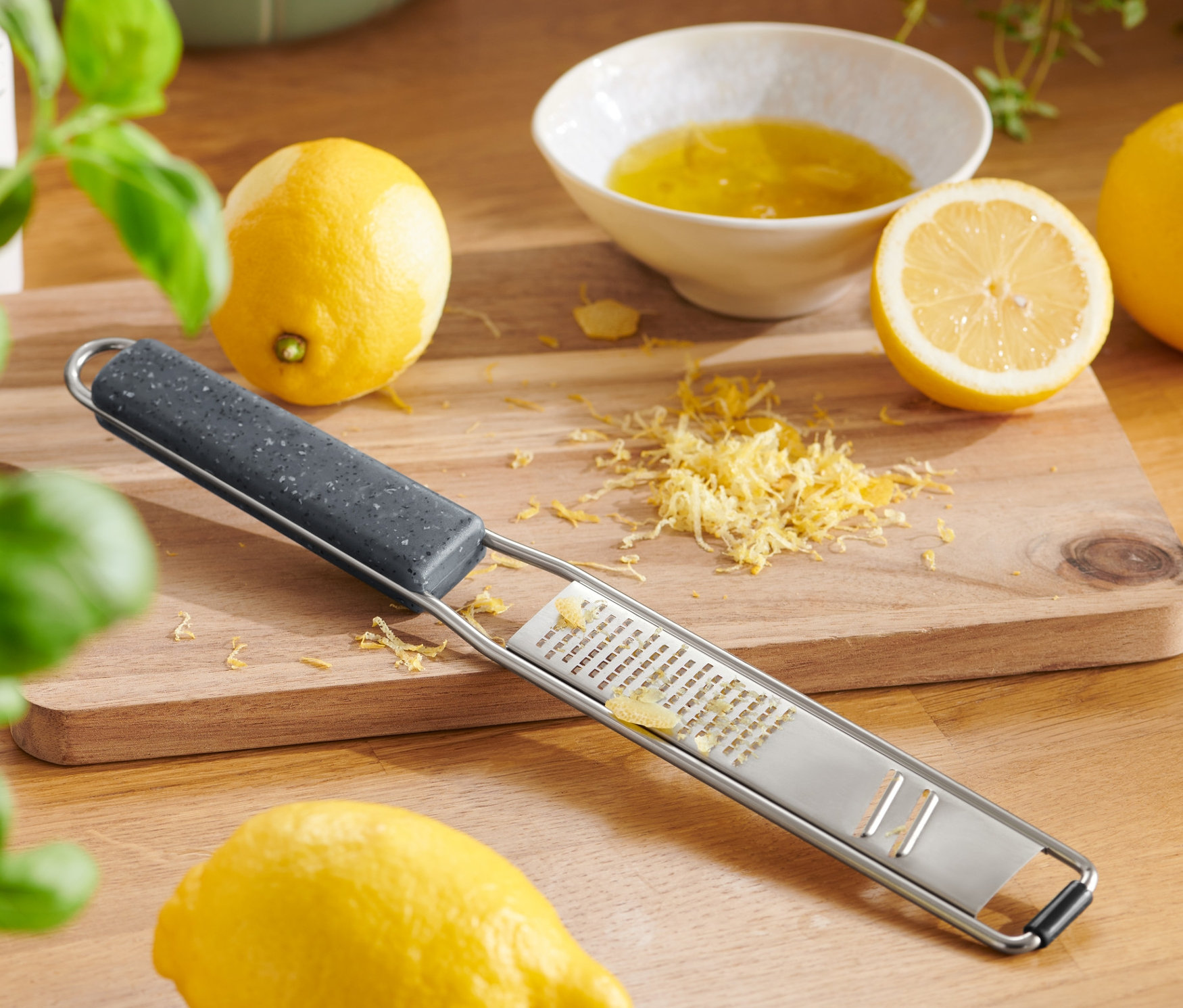 Eine 2-in-1-Handreibe liegt auf einem Holzbrett mit Zitronen und Abrieb.