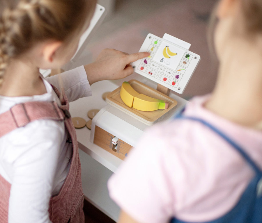 Mädchen an small foot Waage "fresh", tippt auf Display mit Obst- und Gemüse-Symbolen.