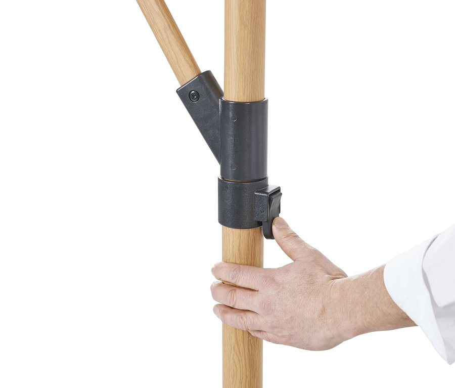 Eine Hand betätigt den Mechanismus eines beige Leco Ampelschirm Ø 300 cm, inkl. Schirmständer und Abdeckhaube.