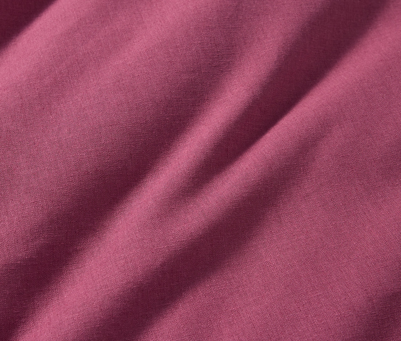 Nahaufnahme der Halbleinen-Bettwäsche in Normalgröße in einem tiefen Rosaton.