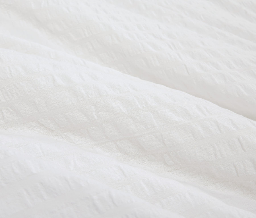 Detailaufnahme eines weißen, strukturierten Stoffes.