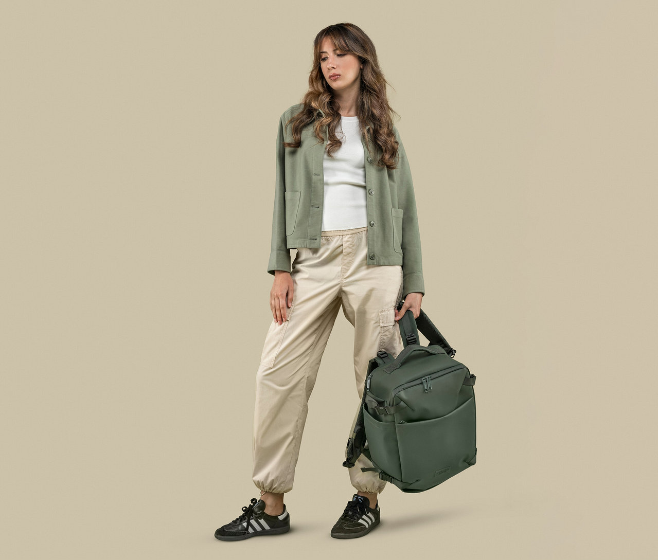 Frau hält einen grünen Tucano TUGO DRY Kabinenrucksack mit 15,6"-Laptopfach.