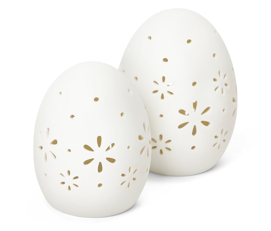Zwei weiße Deko-Eier mit ausgestanzten Blumenmustern stehen auf einem weißen Hintergrund.