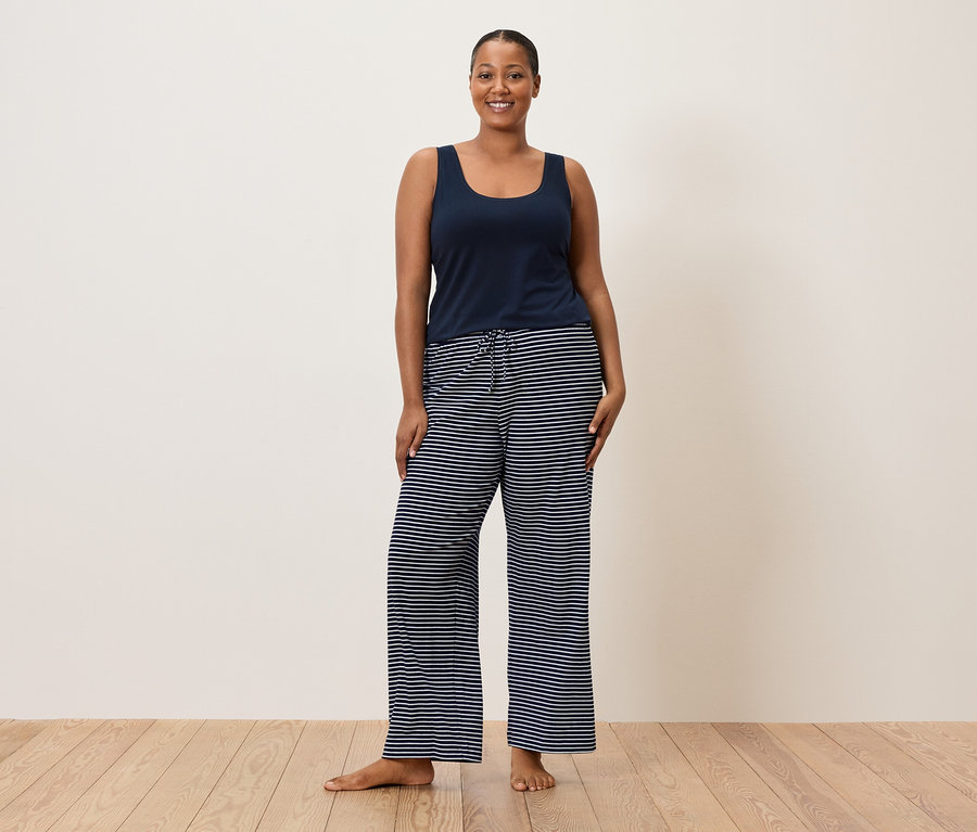 Frau trägt ein blaues Hemdchen und eine gestreifte Hose.