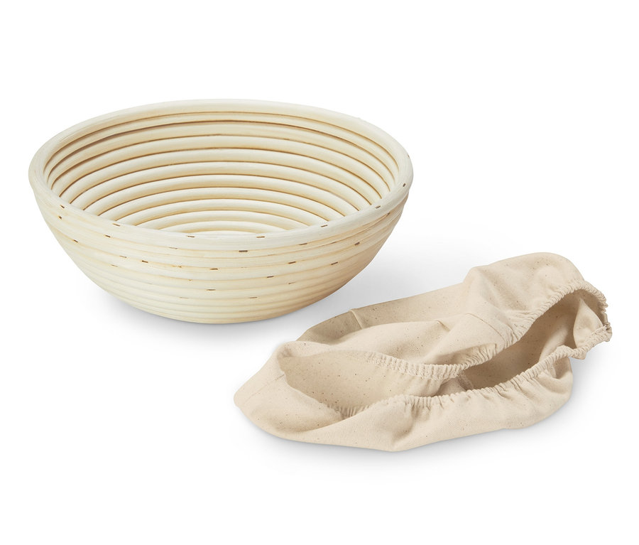 Ein leeres, rundes Gärkörbchen und eine beige Stoffhülle.