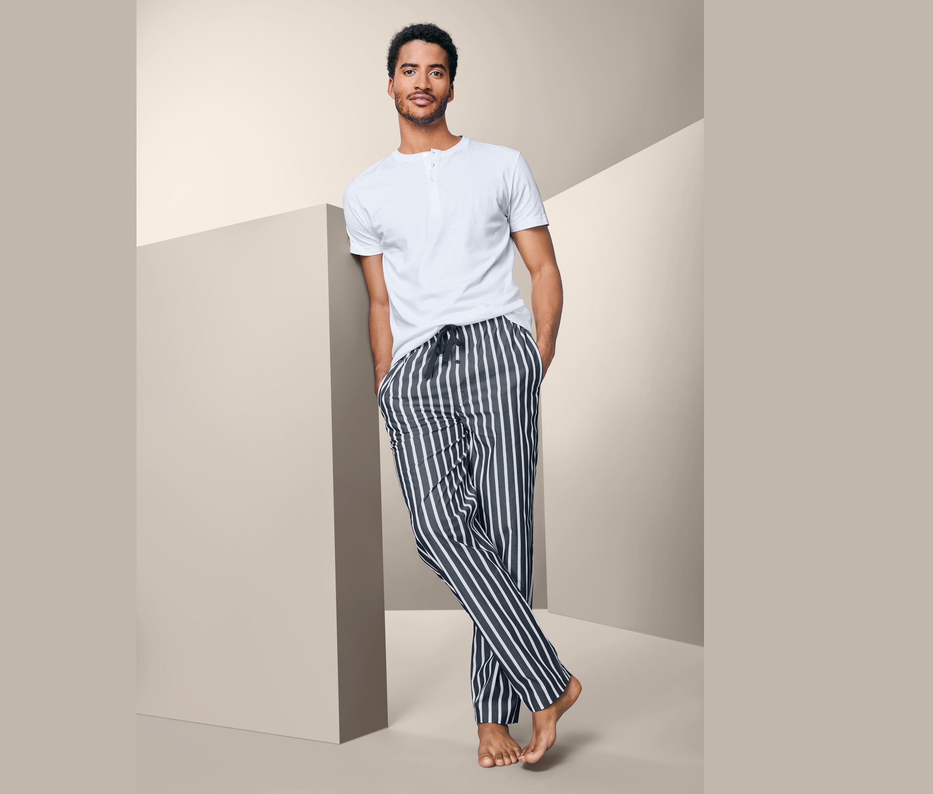 Mann an Wand gelehnt trägt Pyjama.