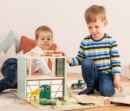 Zwei Jungen spielen mit dem Pinolino Spielwelt »Reiterhof Lise« aus Holz.