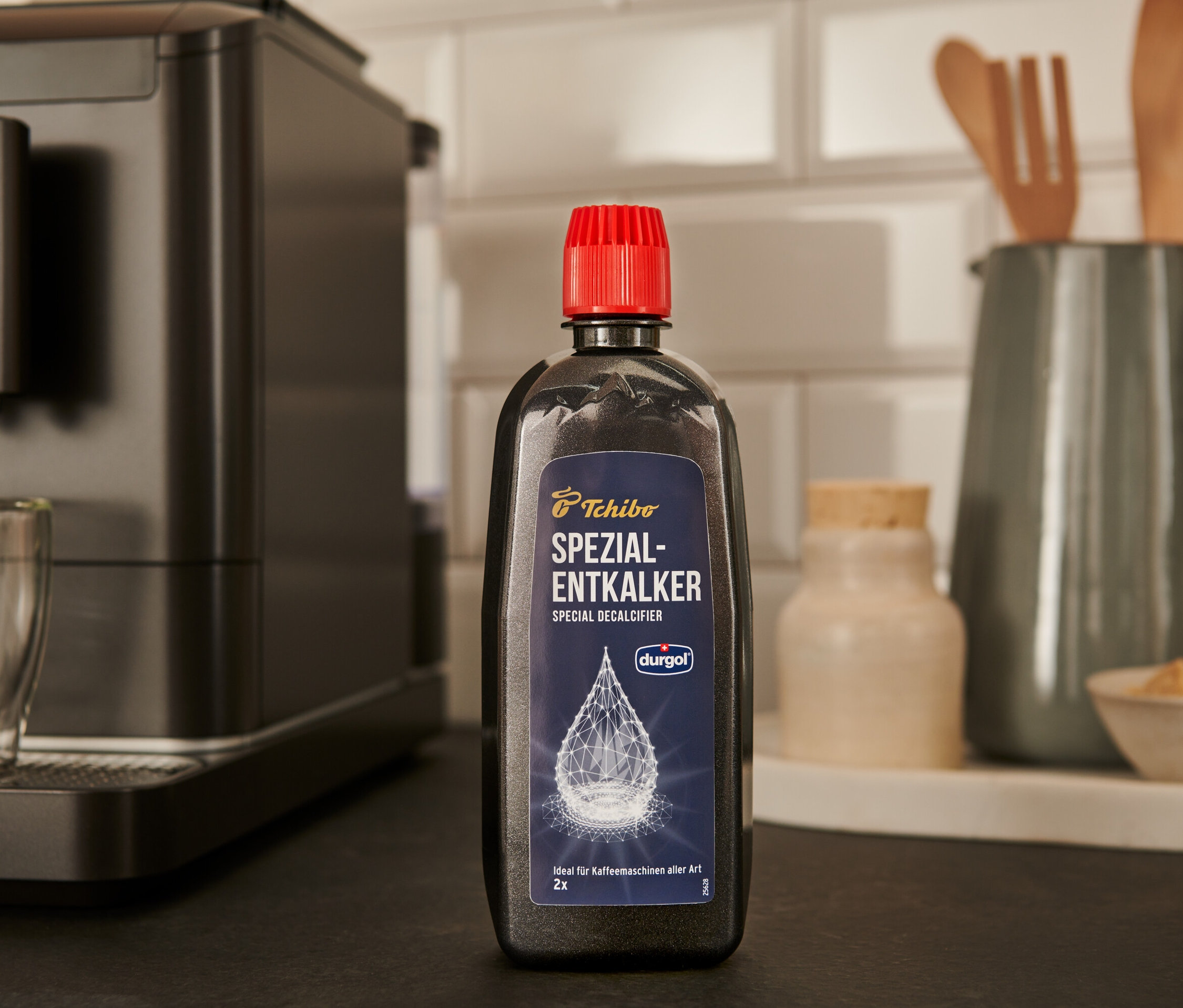 Eine schwarze Flasche durgol® Spezial-Entkalker, 400 ml, steht auf der Theke neben einer Kaffeemaschine.