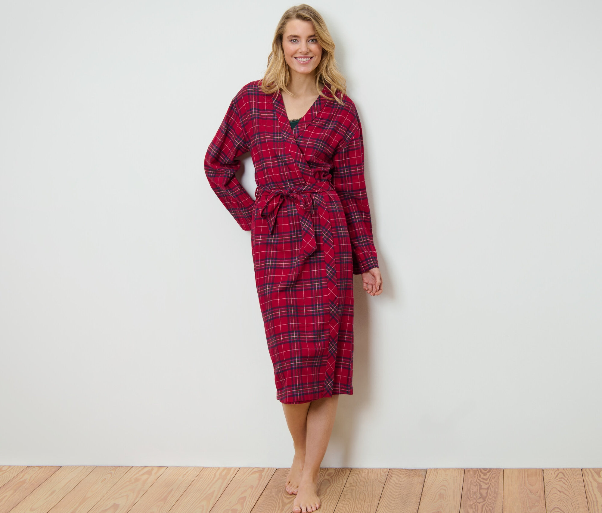 Blonde Frau steht und trägt einen rot karierten Flanell-Morgenmantel.
