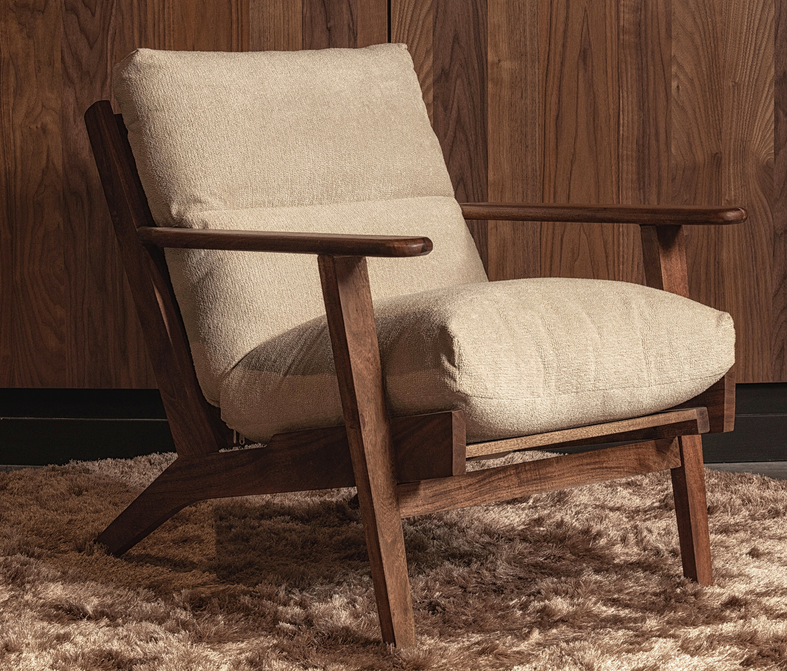 BePureHome Sessel »Housten« aus Bouclé/Holz natur steht auf einem zotteligen Teppich.