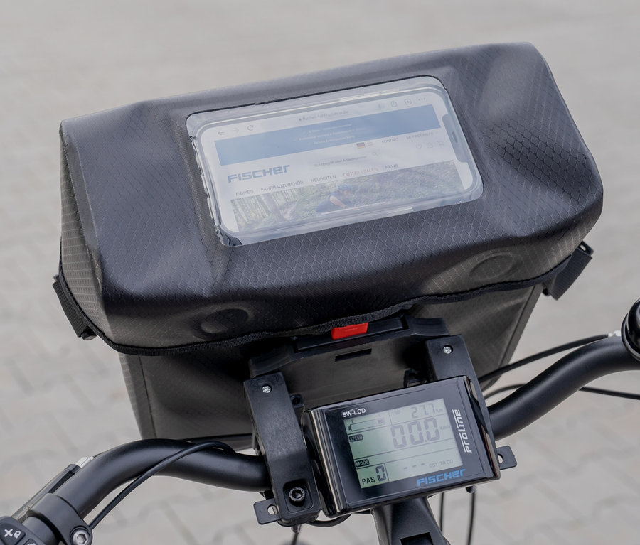 Nahaufnahme einer Fahrradlenkstange mit montierter schwarzer FISCHER Lenkertasche PLUS+ Terra und einem digitalen Display.