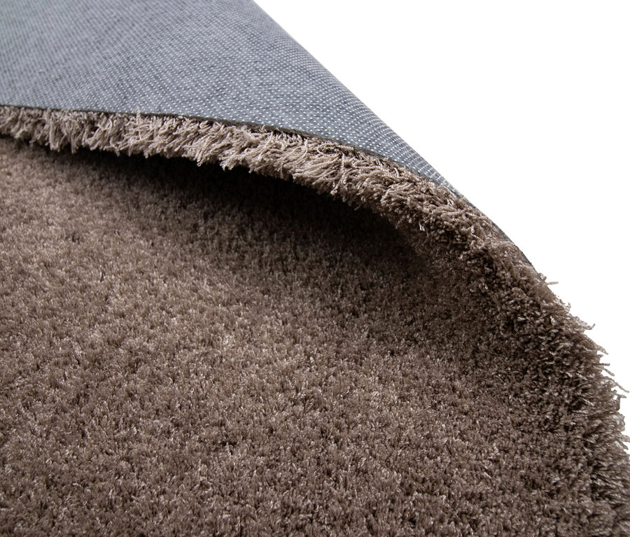 Nahaufnahme eines aufgerollten, zotteligen, beigefarbenen Teppichs »Pleasure«.
