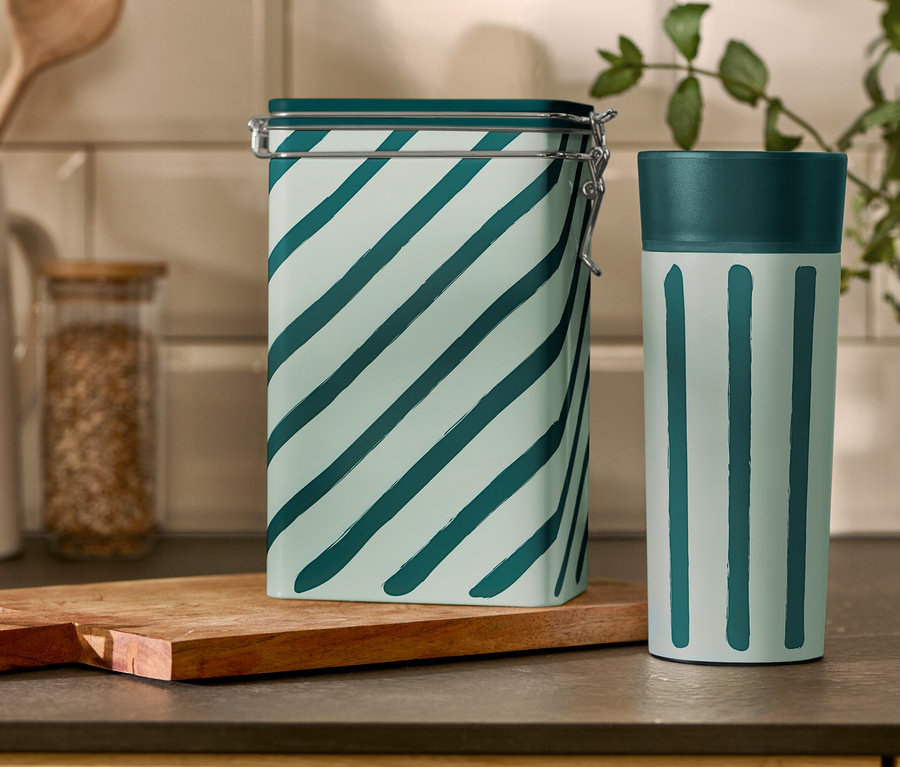 Gestreifte Kaffeedose und Coffee-to-go-Becher stehen auf einem Küchentisch.