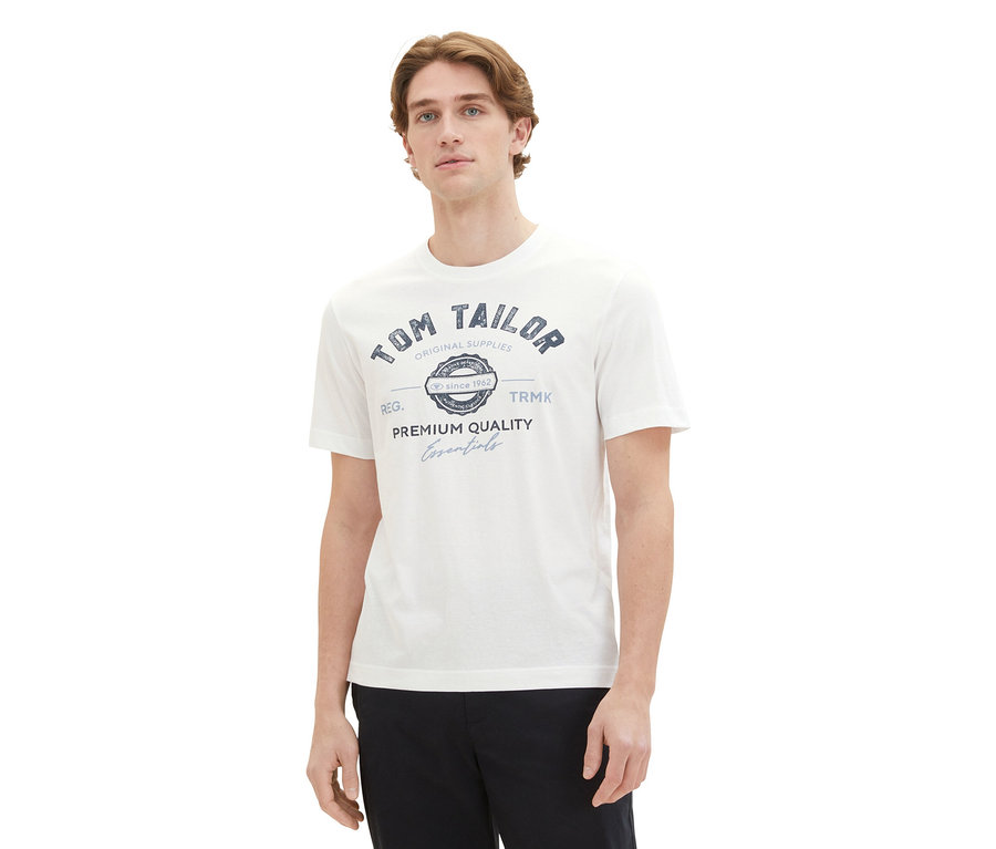 Mann trägt ein weißes Tom Tailor T-Shirt mit Logo und schwarze Hose.