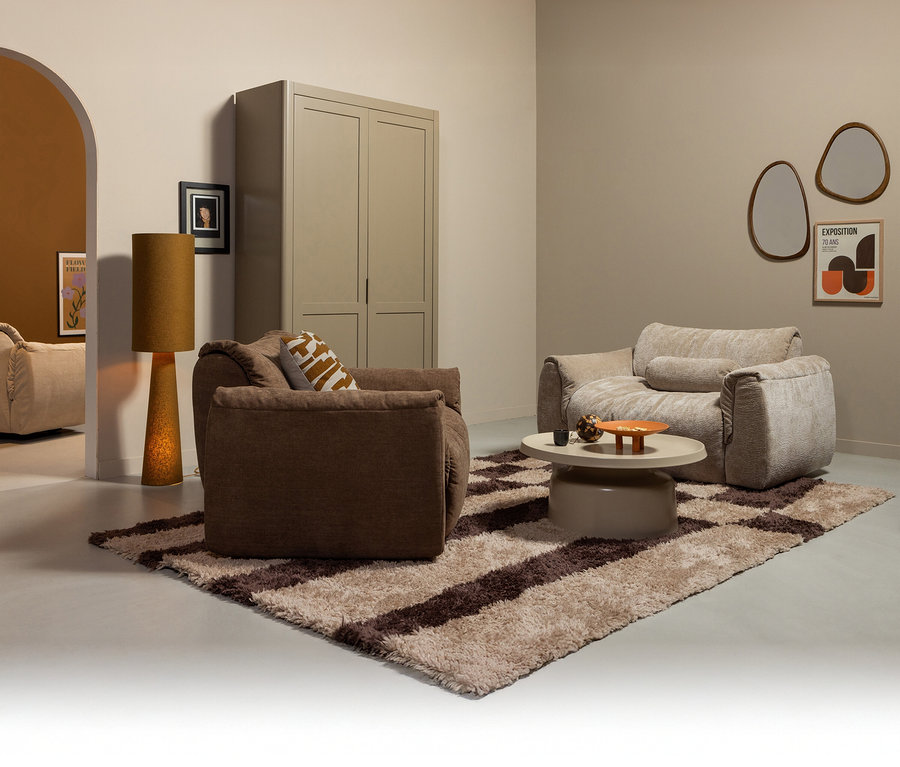 Wohnzimmer mit zwei Sesseln, einem Couchtisch und einem Teppich in Braun- und Beigetönen.