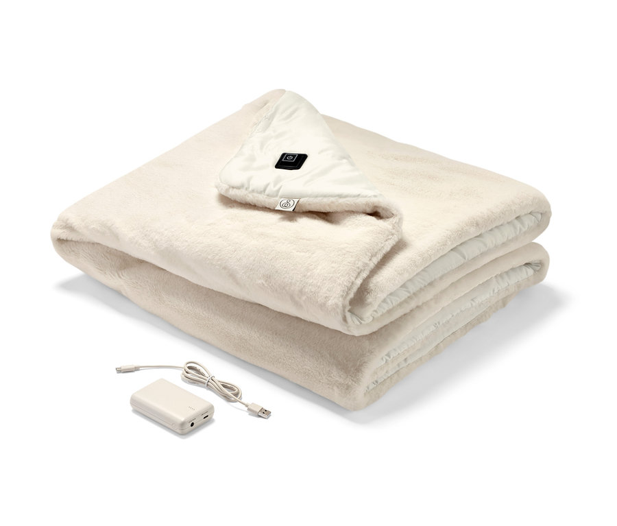 Ein zusammengelegter Akku-Heizponcho in Creme mit sichtbarem Bedienfeld und Akku.
