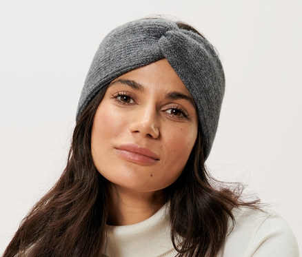 Frau sitzt auf einem Stuhl und trägt ein graues Stirnband mit Wolle.