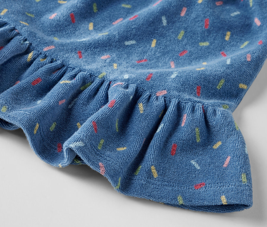 Detailansicht eines Kinder-Frottier-Rocks mit Rüschen und farbigem Aufdruck.