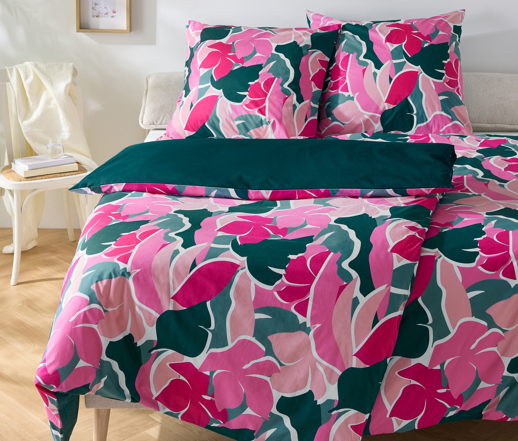 Blumige Perkal-Bettwäsche, zwei Normalgrößen und eine Übergröße, liegen auf einem Bett.