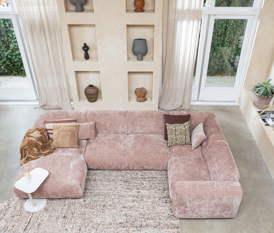 Vogelperspektive eines Wohnzimmers mit einem rosa Sofa, einem beigen Woood Efia Teppich und Dekorationen in Wandnischen.