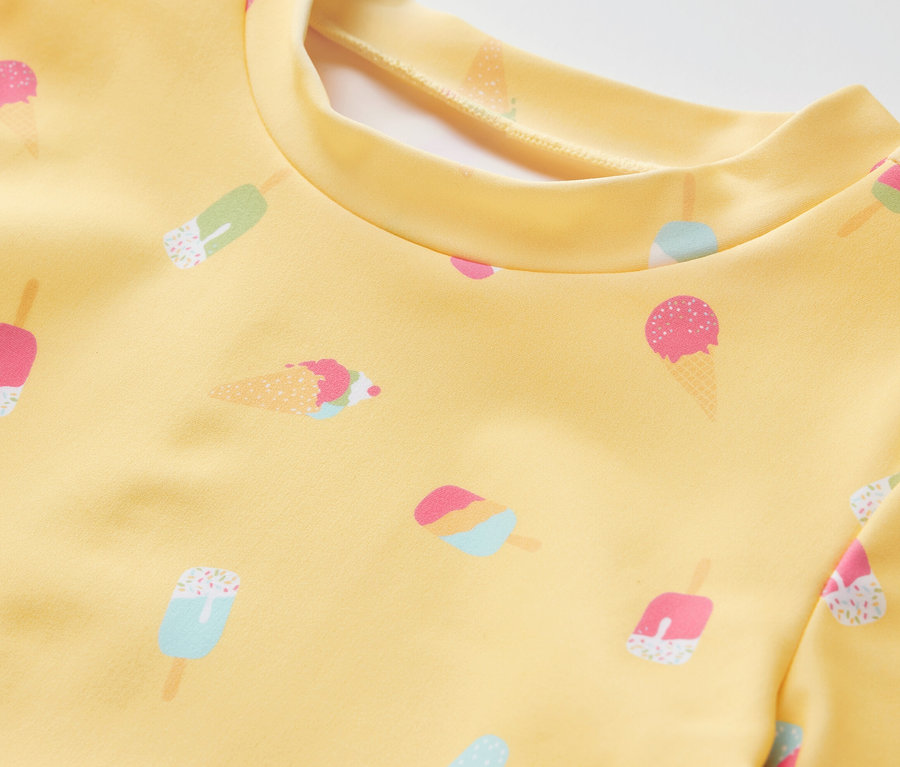 Detailaufnahme eines gelben Kinder-Kombis mit UV-Schutzfaktor 80 und Eis-Muster.