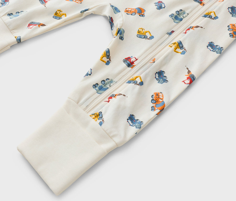 Nahaufnahme eines langärmeligen Strampelanzugs mit Reissverschluss und Baufahrzeugmuster.