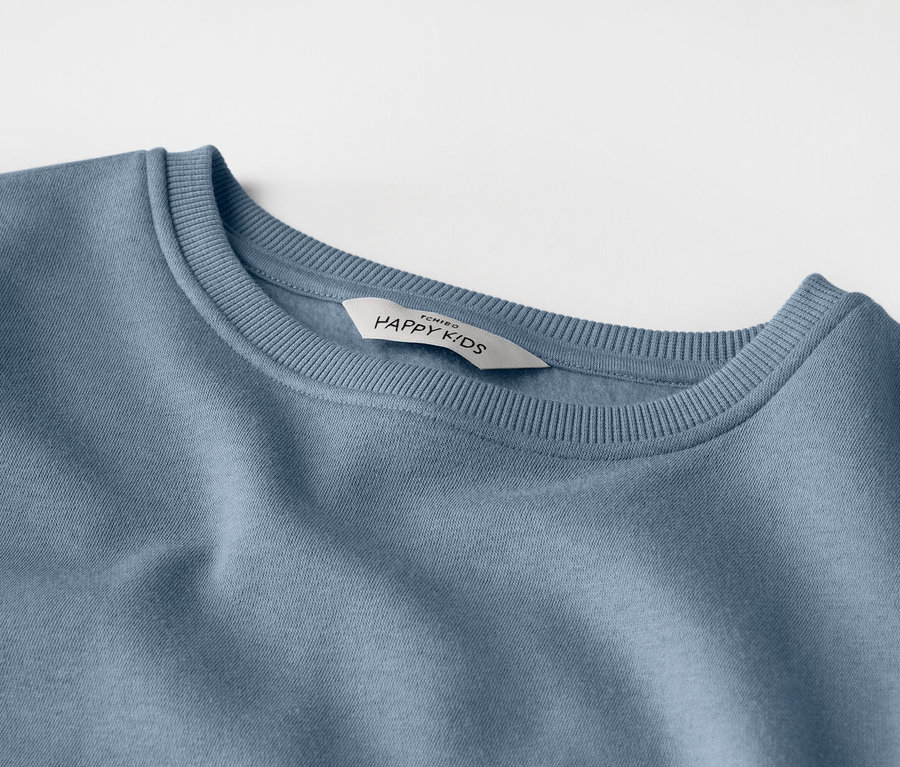 Nahaufnahme eines hellblauen Kinder-Sweatshirts mit einem Etikett mit der Aufschrift "HAPPY KIDS".